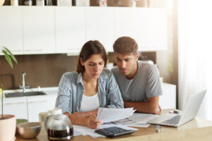 Busy couple having financial problems, looking at papers sended from bank, asking them to pay their bills in nearest future, not knowing what to do, calculating their family budget. People, finances